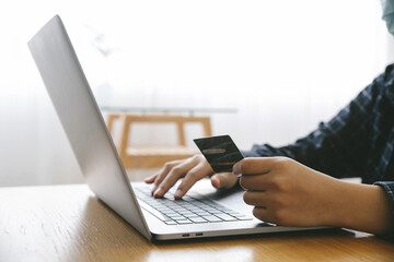 Man Holding credit card and using a laptop with shopping online to buy a gift for girlfriend at the cafe. Black Friday and shopping online Concept.