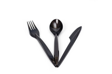 A set of plastic cutlery knife, fork and spoon in black, filmed on a white background