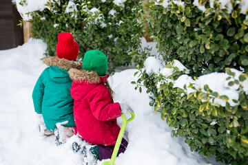 Rear view of girls playing with snow, building an igloo. Siblings having fun outside on snow day....