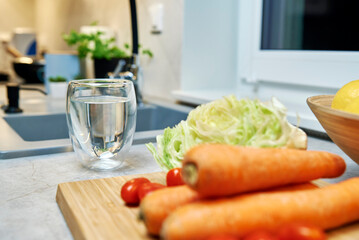 Glass of pure water and fresh vegetables on table