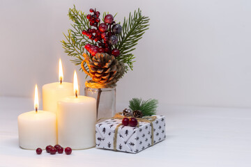 Christmas candles with a gift box and a pine branch on a white background. New Year card. Christmas collection Close up