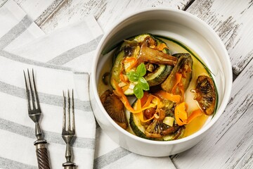 Zucchini with mushrooms and carrots. Baked vegetables with edible mushrooms. Healthy and delicious vegetarian food. Organic food on a rustic background. Close-up