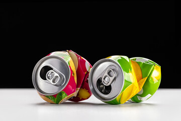 Waste recycling and disposal concept. Two crumpled beverage cans on a dark background.