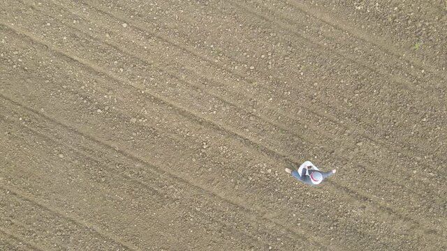 Aerial view above a sower planting seeds on a bare field - top down, drone shot