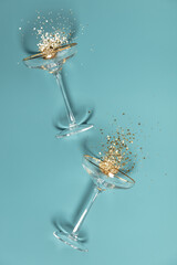 Two champagne glasses with splash of confetti over creative background © Natalia Klenova