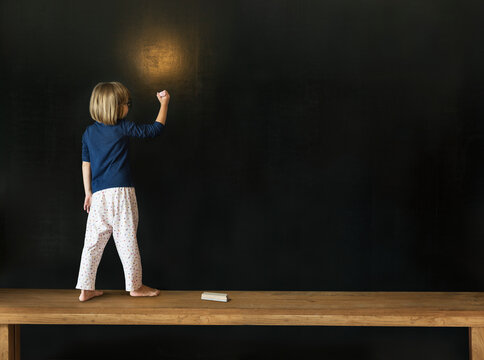 Little girl drawing on a blackboard