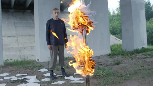 Man burning white paper sheets on ground