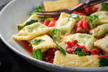Italian square ravioli with basil, tomato sauce and broccoli in a plate close-up. Pasta ravioli with vegetables