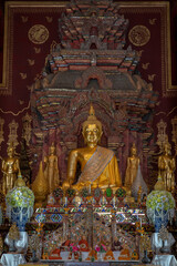 Fototapeta na wymiar Ancient golden Buddha statues with traditional Lanna style decor inside main vihara at historic Wat Chiang Man buddhist temple, the oldest in Chiang Mai, Thailand