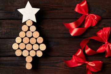 Christmas tree from wine corks with a star on top on a wooden background with red bows