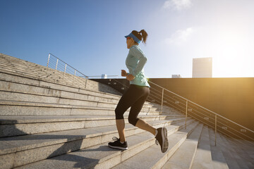 Fitness sports woman running up stairs in sunrise city