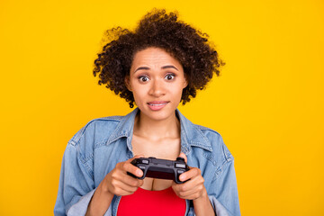Fototapeta na wymiar Photo of young worried young dark skin woman hold hands joystick play game isolated on yellow color background