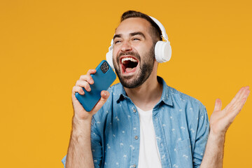 Young expressive happy caucasian man 20s in blue shirt white t-shirt headphones listen to music...
