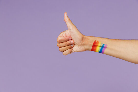 Cropped close up photo shot of gay man male hand arm showing thumb up like positive gesture free area isolated on plain pastel purple color background studio. People lifestyle fashion lgbtq concept