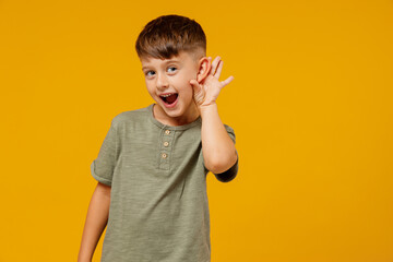 Little small smiling happy boy 6-7 years old in green t-shirt try to hear you overhear listen...