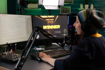 Person live streaming video games on monitor. Woman broadcasting gameplay, playing online on stream with live chat, using monitor and microphone. Streamer wearing headphones to play.