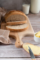 Sliced fresh bread toast with butter on a wooden cutting board.