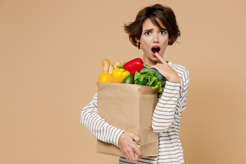 Young shocked scared astonished surprised vegetarian woman in casual clothes hold paper bag with...