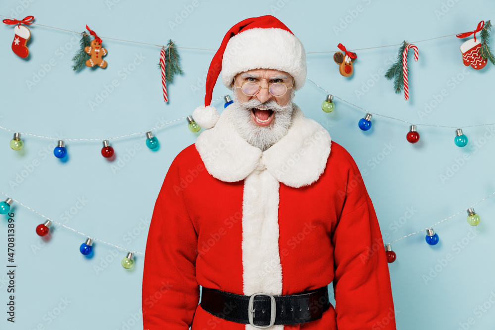 Wall mural Old sad angry bearded Santa Claus man 50s wears Christmas hat red suit clothes shout scream isolated on plain blue background studio. Happy New Year 2022 celebration merry ho x-mas holiday concept