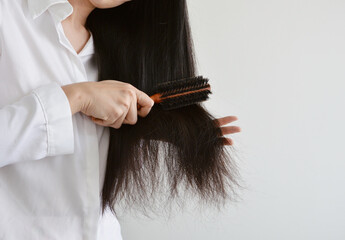 Asian woman combing her black hair with a round wooden brush