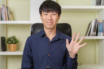 Portrait webcam of happy young adult Asian businessman is smiling, waving hands when talk on...