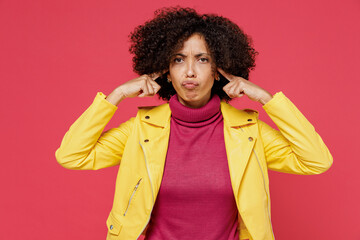 Nervous displeased irritated young curly black latin woman 20s years old wear yellow jacket cover ears with hands fingers do not want to listen scream isolated on plain red background studio portrait