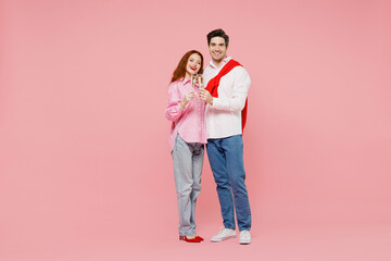 Full body young couple two friends woman man 20s in shirt look camera hold wineglass with champagne raise toast isolated on plain pastel pink background Valentine's Day birthday holiday party concept