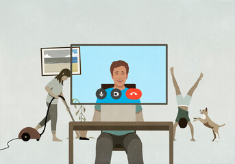 Man video chatting from home at computer with family in background
