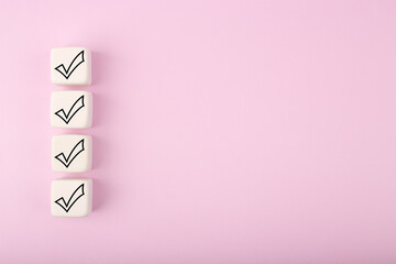 Four black checkmarks on white toy cubes in a row against bright pastel purple background with copy...