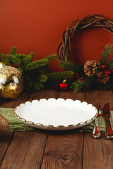 Empty white plate at served Christmas table among decorations.