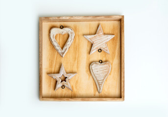 Top view of Christmas wooden decorations with hearts and stars in a wooden frame.
