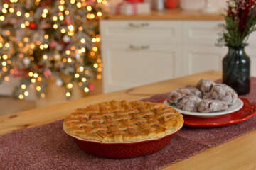 American pie with cherries and grating, Christmas gingerbread on the table against the backdrop of a Christmas tree, golden bokeh and kitchen.