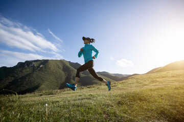 Young woman ultramarathon runner running at mountain top