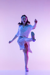 Portrait of young excited woman in vintage retro style clothes dancing isolated on lilac color...