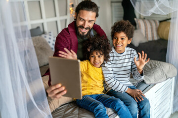 Happy father and children playing with digital tablet. Multiethnic family fun technology concept