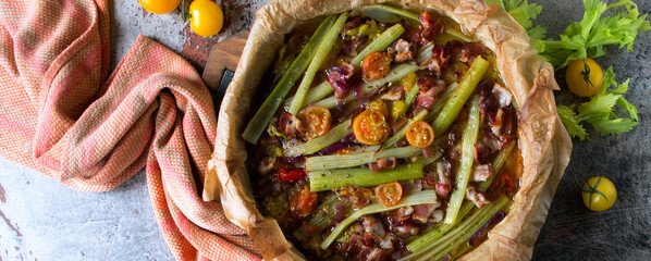 baking sheet with baked celery with tomatoes and bacon on the table