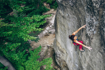 Obraz premium Beautiful Woman Climbing on the High Rock in the Mountains. Adventure and Extreme Sport Concept