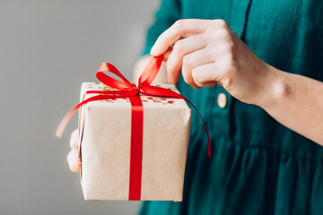 Woman hands holding present box with red bow. Preparing for Christmas holidays