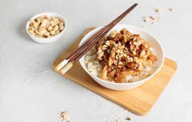 Bowl with chinese food. Kung pao, rice with chicken fillet in sauce. Close-up on a light background, horizontal, copy space