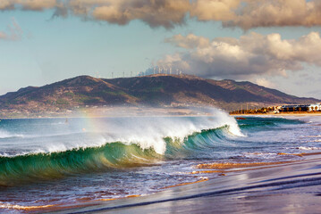 Ocean wave with swell breaking on the beach at sunrise with easterly wind, Los Lances beach,...