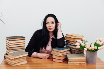 beautiful brunette woman in a business suit learns to read books at the table