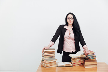 beautiful brunette woman in a business suit teacher with books at the table