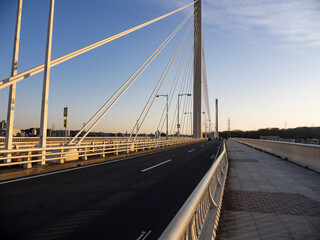 多摩川に掛かる橋の道路風景。夕陽に照らされる府中四谷橋。