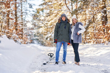 Fototapeta na wymiar Couple having fun with sledge on snow in winter