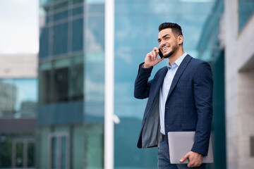 Happy middle eastern young entrepreneur having phone conversation