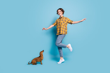 Photo of cute cheerful lady enjoy rest play with dog wear plaid shirt jeans sneakers isolated blue color background