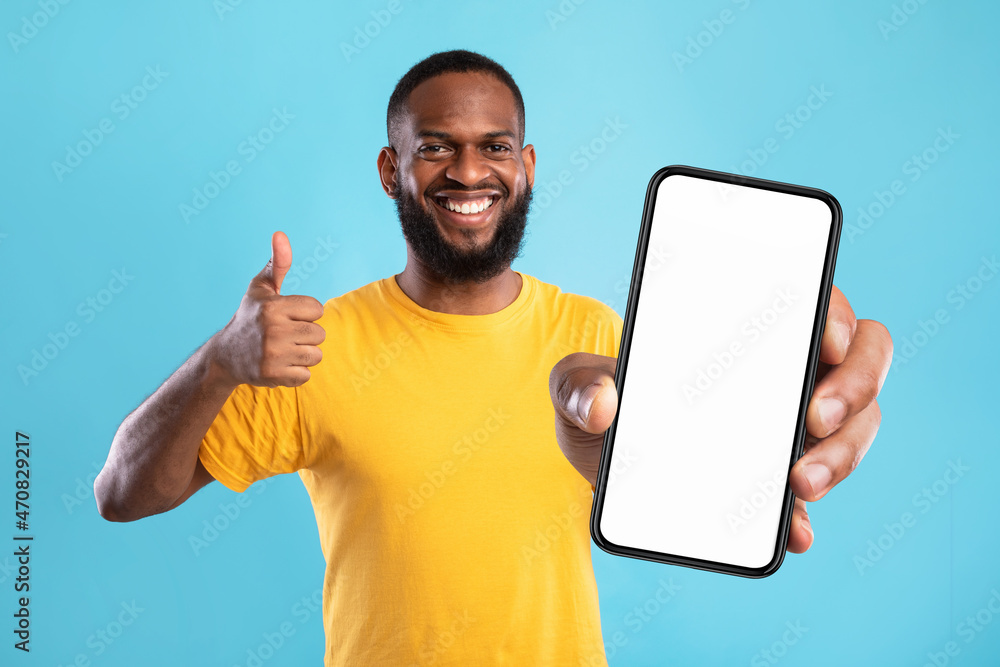 Poster black guy demonstrating cellphone with empty screen, showing thumb up, recommending website, offerin