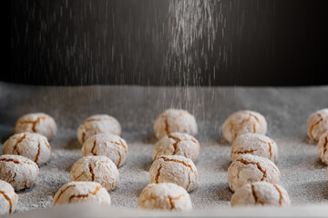 Amaretti - traditional italian almond cookies in sugar powder on baking paper.
