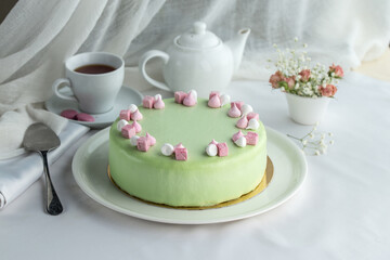 Modern French mousse cake with green glaze ad cup of tea on the table