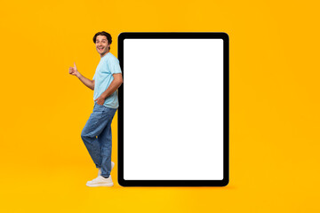 Happy man showing white empty tablet screen and thumbs up